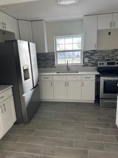 kitchen featuring light countertops, appliances with stainless steel finishes, a sink, and white cabinetry