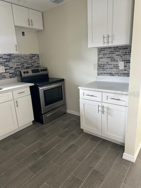 kitchen with light countertops, wood tiled floor, white cabinets, and stainless steel range with electric cooktop