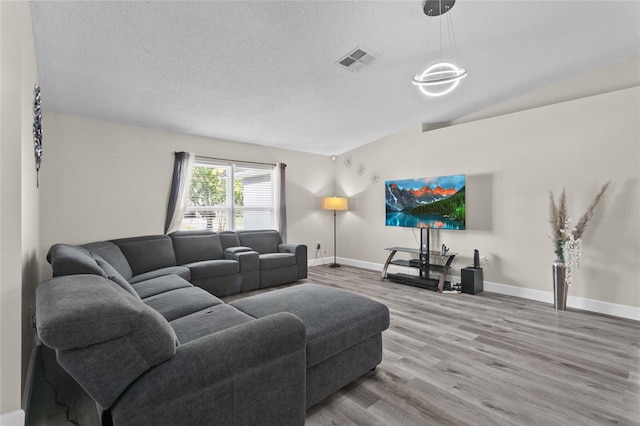 living area featuring baseboards, a textured ceiling, visible vents, and wood finished floors