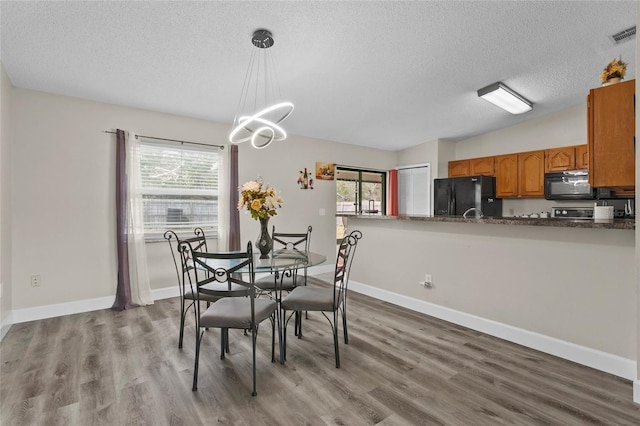 dining area with visible vents, baseboards, light wood-style flooring, a textured ceiling, and a chandelier