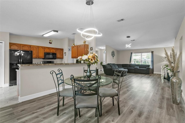 dining room with light wood-style floors, visible vents, and baseboards