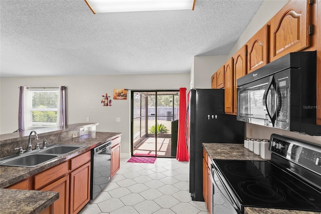 kitchen featuring dark countertops, black appliances, brown cabinetry, and a sink