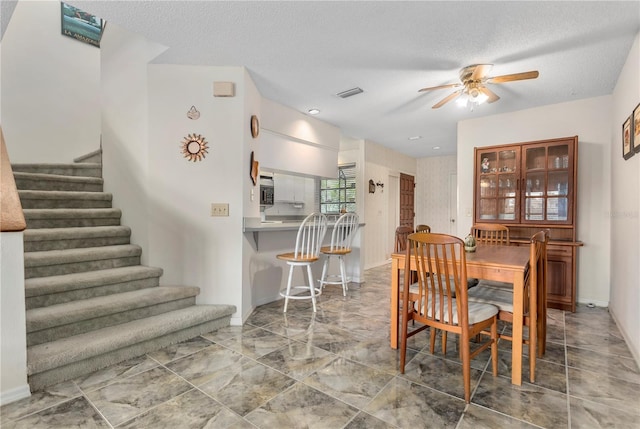 dining area with ceiling fan and a textured ceiling