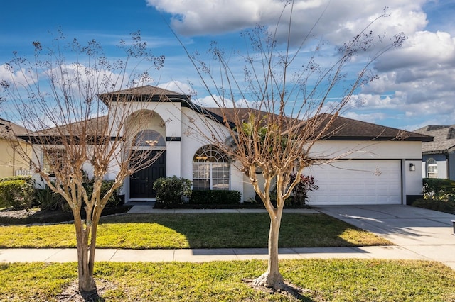 view of front facade with an attached garage, driveway, a front lawn, and stucco siding