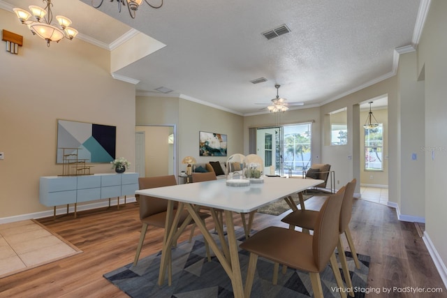 dining space featuring baseboards, visible vents, wood finished floors, crown molding, and a textured ceiling