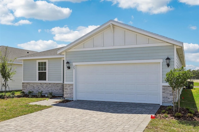 ranch-style home with decorative driveway, stone siding, and board and batten siding
