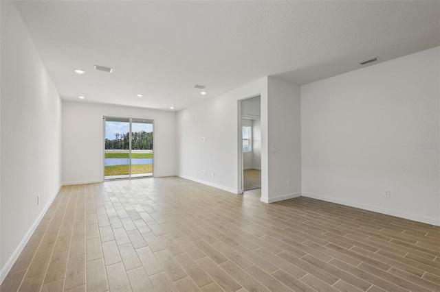 spare room featuring baseboards, visible vents, and light wood-style floors