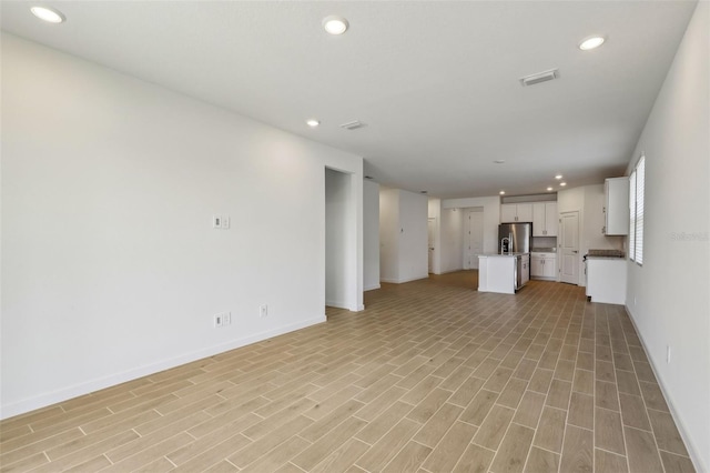 unfurnished living room with baseboards, light wood-style flooring, visible vents, and recessed lighting