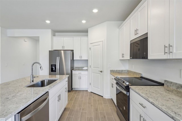 kitchen with white cabinets, light wood-style flooring, a sink, recessed lighting, and appliances with stainless steel finishes