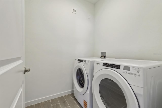 laundry area with baseboards, visible vents, independent washer and dryer, wood tiled floor, and laundry area