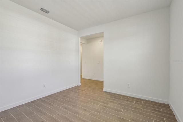 unfurnished room with baseboards, wood finished floors, and visible vents