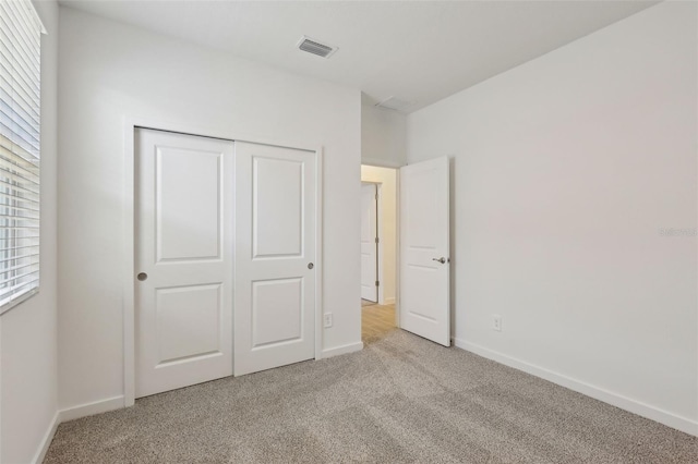unfurnished bedroom with baseboards, visible vents, a closet, and carpet flooring