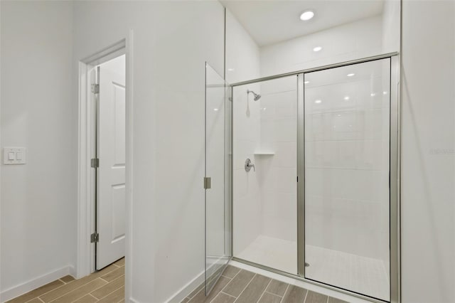 full bath featuring a shower stall, wood finish floors, and baseboards
