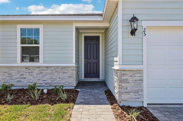 property entrance featuring a garage and stone siding