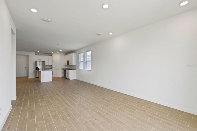 unfurnished living room featuring recessed lighting, light wood-style flooring, visible vents, and baseboards