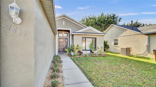 property entrance with a yard and central AC unit