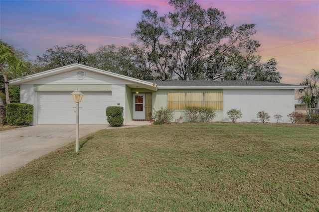 single story home featuring a garage and a lawn