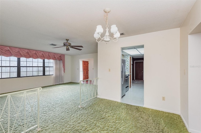 spare room featuring ceiling fan with notable chandelier, light colored carpet, and a textured ceiling