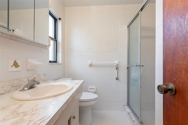 bathroom featuring a shower with shower door, tile walls, vanity, toilet, and tile patterned floors