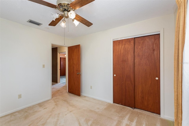 unfurnished bedroom featuring light carpet, a textured ceiling, and a closet