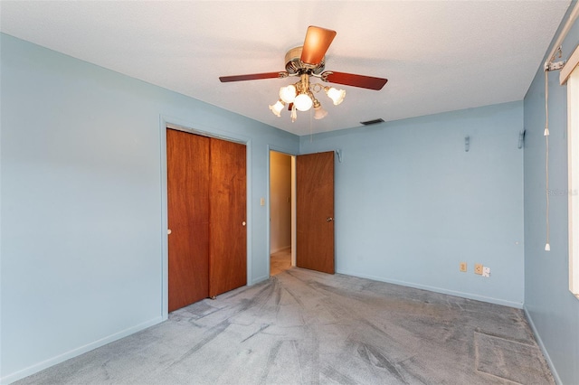 unfurnished bedroom with ceiling fan, light colored carpet, a closet, and a textured ceiling