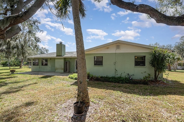 back of house featuring a lawn and a patio