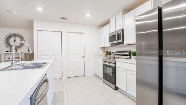 kitchen with white cabinetry, sink, light tile patterned floors, and stainless steel appliances