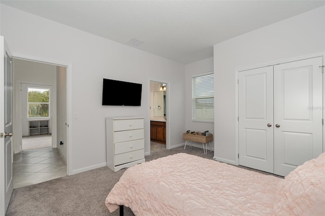 carpeted bedroom featuring ensuite bathroom and a closet