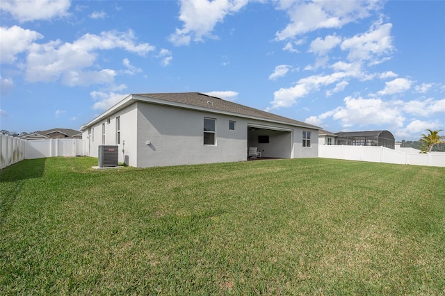 back of property with central AC and a lawn