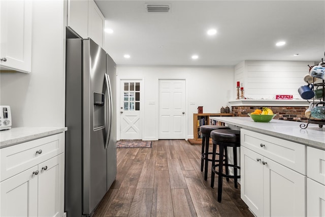 37224 Apiary Rd, Grand Island, FL 32735 - kitchen with stainless steel fridge with ice dispenser, dark wood-style floors, a breakfast bar, white cabinetry, and light stone countertops