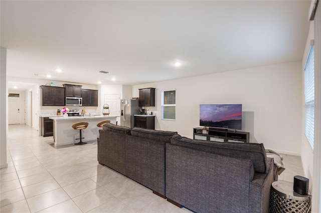 living room featuring light tile patterned floors, baseboards, visible vents, and recessed lighting