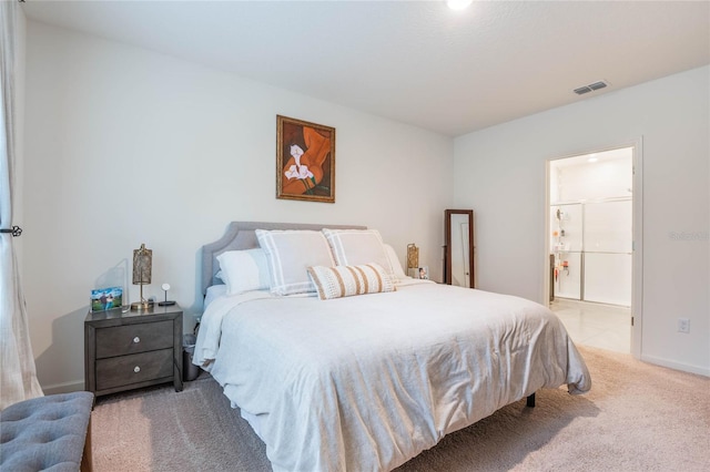 bedroom with ensuite bath, baseboards, visible vents, and light colored carpet