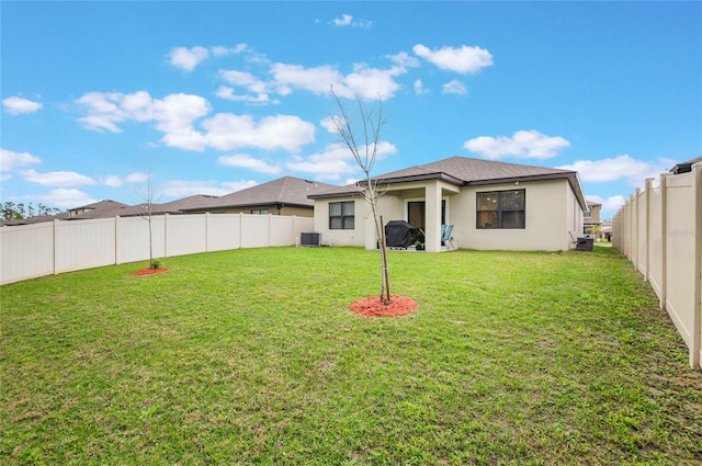 rear view of house with a fenced backyard, central AC, a lawn, and stucco siding