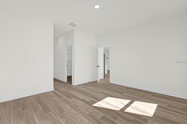 unfurnished room with baseboards, visible vents, wood finished floors, and recessed lighting