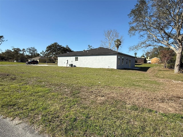 view of side of property featuring a lawn and stucco siding