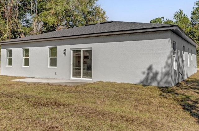 rear view of property featuring stucco siding, a lawn, and a patio