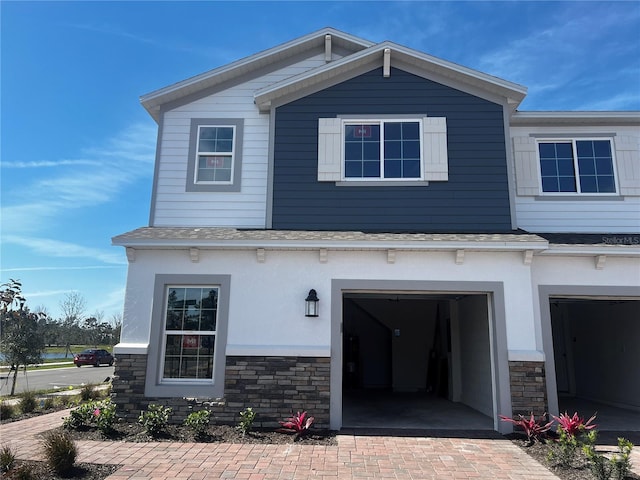 view of front of home featuring decorative driveway, stone siding, and an attached garage