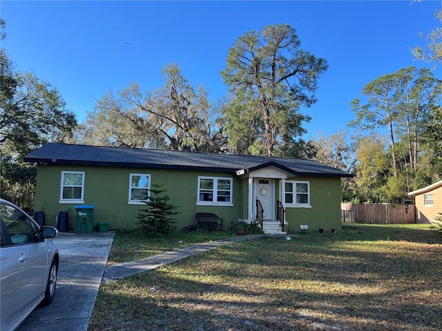 view of front of house with stucco siding, a front yard, and fence