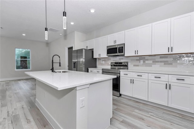 2844 SW 162nd Street Rd, Ocala, FL 34473 - kitchen featuring sink, white cabinetry, decorative light fixtures, appliances with stainless steel finishes, and a kitchen island with sink