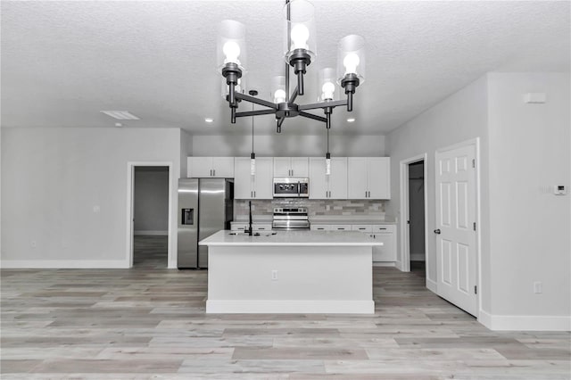 2844 SW 162nd Street Rd, Ocala, FL 34473 - kitchen featuring appliances with stainless steel finishes, a kitchen island with sink, hanging light fixtures, an inviting chandelier, and white cabinets