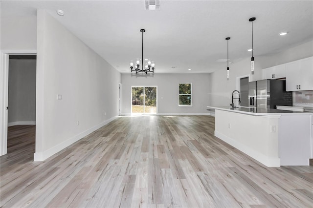 2844 SW 162nd Street Rd, Ocala, FL 34473 - kitchen featuring pendant lighting, light wood-type flooring, white cabinets, stainless steel fridge, and an inviting chandelier