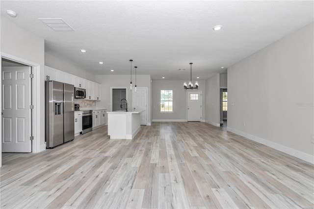 2844 SW 162nd Street Rd, Ocala, FL 34473 - kitchen with appliances with stainless steel finishes, decorative light fixtures, an island with sink, white cabinets, and light hardwood / wood-style flooring