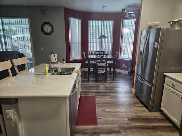 kitchen with sink, white cabinetry, hanging light fixtures, a center island with sink, and stainless steel appliances