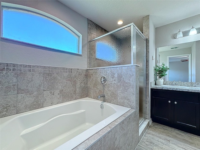 full bathroom with visible vents, a stall shower, a textured ceiling, a bath, and vanity