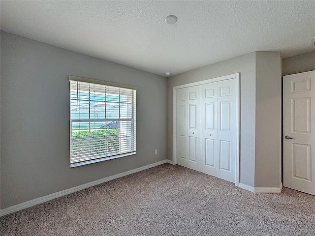 unfurnished bedroom featuring carpet, baseboards, a closet, and a textured ceiling