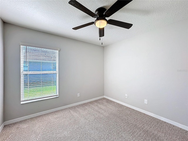 spare room with a wealth of natural light, a textured ceiling, baseboards, and carpet floors