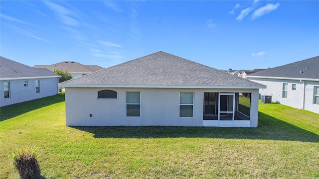 rear view of property with stucco siding, a lawn, central AC, and roof with shingles