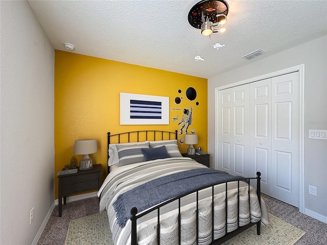 carpeted bedroom featuring visible vents, baseboards, a textured ceiling, and a closet