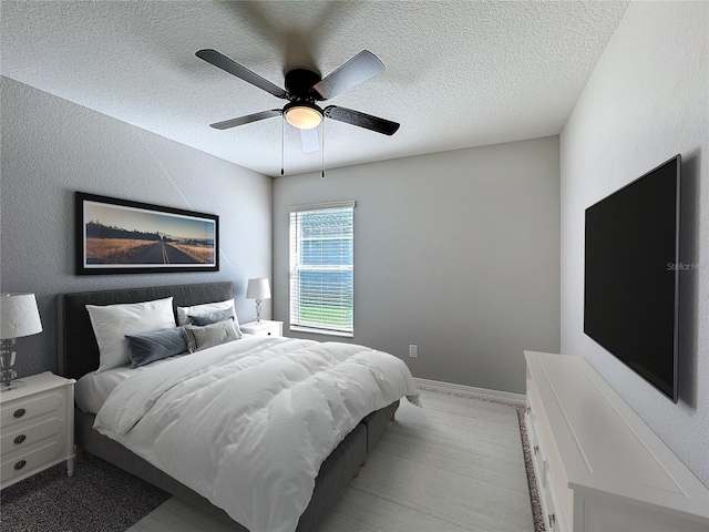 bedroom featuring a ceiling fan, baseboards, a textured wall, and a textured ceiling