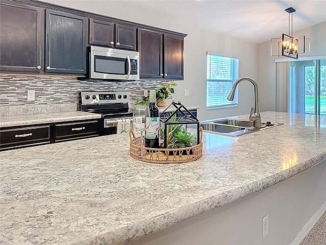 kitchen featuring a sink, stainless steel appliances, dark brown cabinetry, pendant lighting, and backsplash